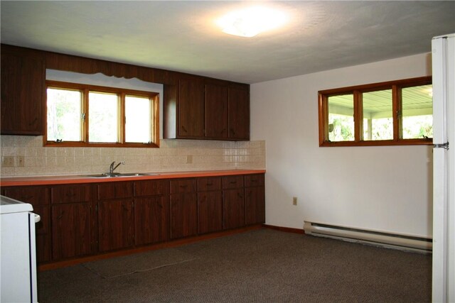 kitchen with a sink, a baseboard heating unit, backsplash, dark carpet, and stove