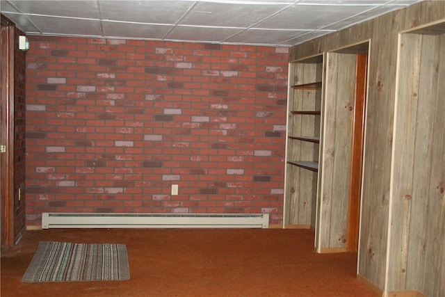 empty room with a baseboard heating unit, wooden walls, carpet flooring, and brick wall