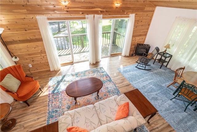 living room featuring a wood stove, hardwood / wood-style flooring, and wooden walls