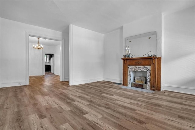 unfurnished living room featuring hardwood / wood-style flooring, a premium fireplace, and a chandelier