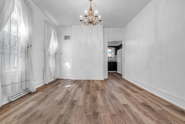 unfurnished living room with a notable chandelier and light wood-type flooring