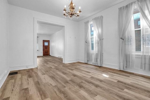 unfurnished dining area with a chandelier and light hardwood / wood-style flooring