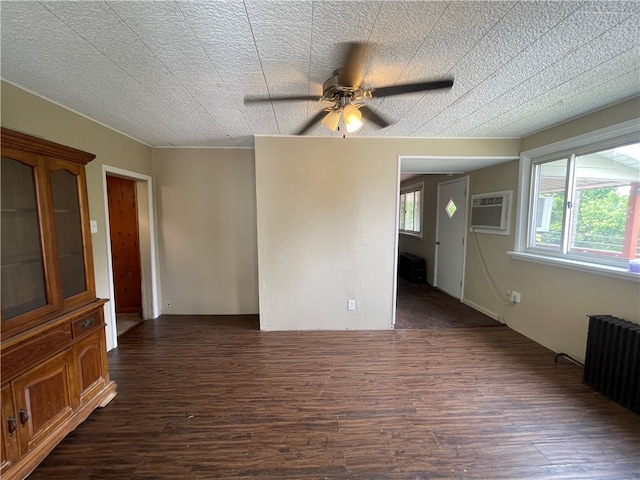 spare room featuring radiator, an AC wall unit, ceiling fan, and dark wood-type flooring