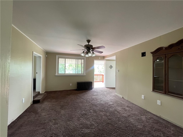 carpeted empty room with ceiling fan and radiator heating unit