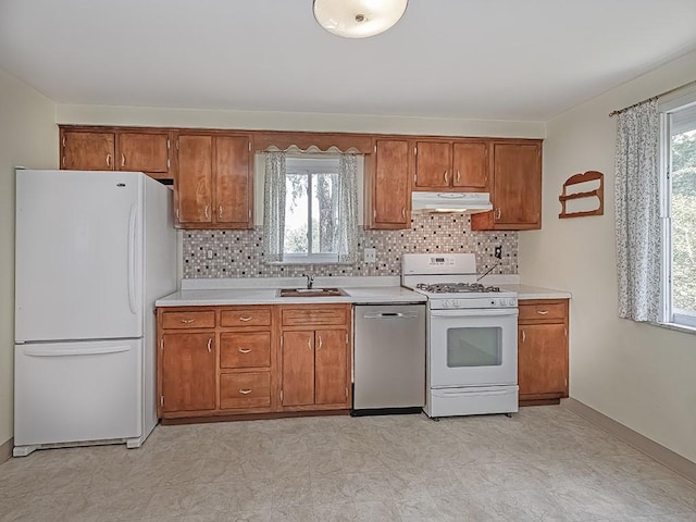 kitchen featuring tasteful backsplash, plenty of natural light, white appliances, and sink