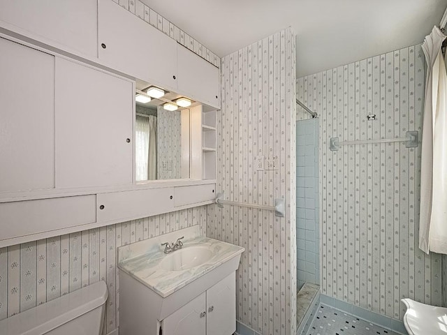 bathroom featuring a tile shower, vanity, and toilet