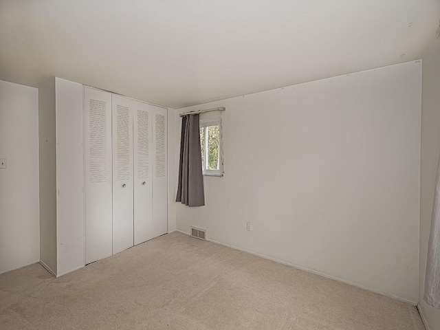 unfurnished bedroom with light carpet and a closet