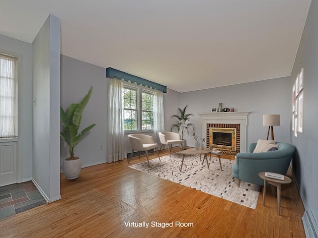 sitting room featuring wood-type flooring and a brick fireplace