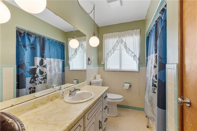 bathroom featuring vanity, tile patterned floors, toilet, and tile walls