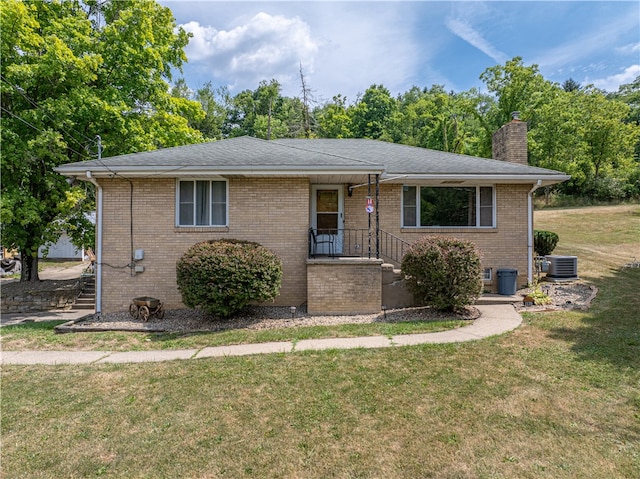 view of front of property with central AC and a front yard