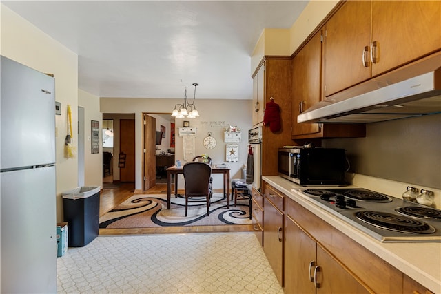 kitchen featuring light hardwood / wood-style flooring, an inviting chandelier, electric cooktop, hanging light fixtures, and white fridge