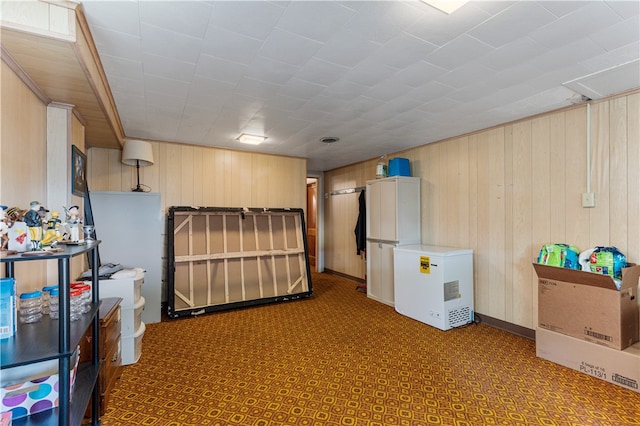 basement featuring refrigerator, tile patterned flooring, and wooden walls