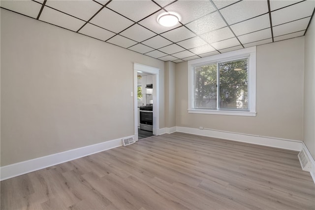 spare room featuring light hardwood / wood-style floors and a drop ceiling