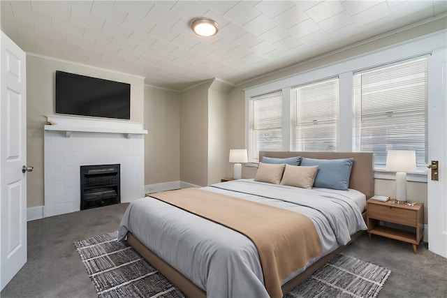 carpeted bedroom featuring crown molding and a tiled fireplace