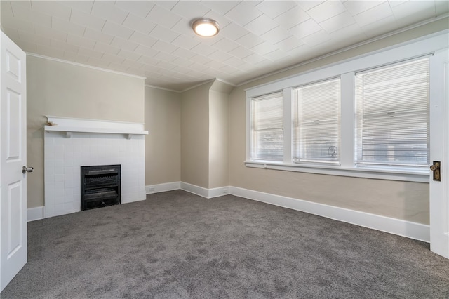 unfurnished living room featuring crown molding, a fireplace, and dark colored carpet