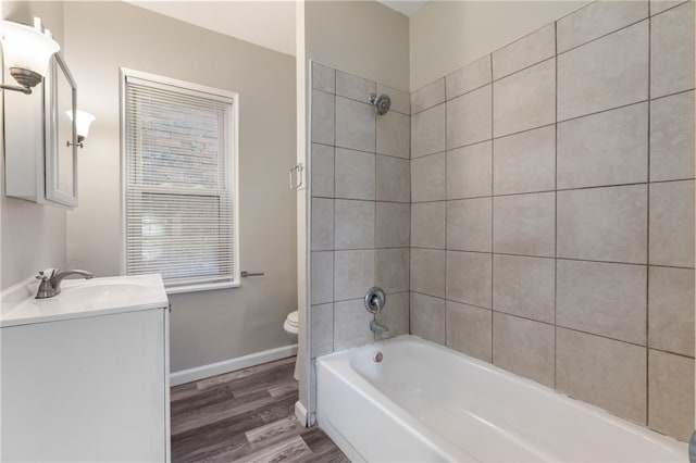 full bathroom featuring vanity, tiled shower / bath combo, wood-type flooring, and toilet