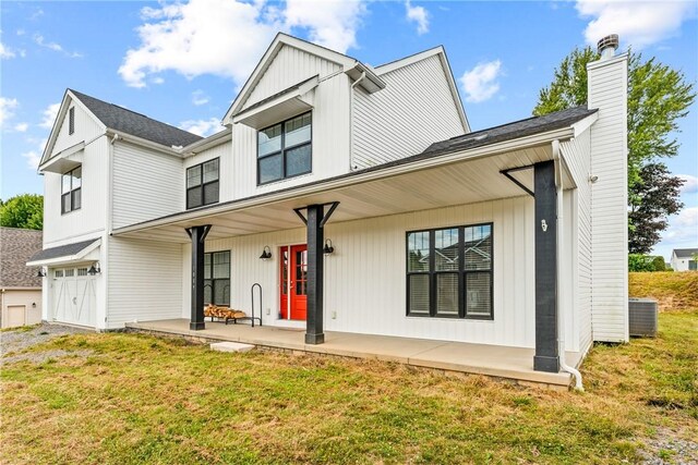 back of house featuring covered porch, central AC, a garage, and a lawn