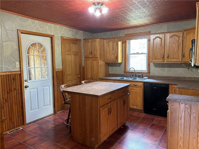 kitchen featuring black dishwasher, sink, dark tile patterned flooring, crown molding, and a center island