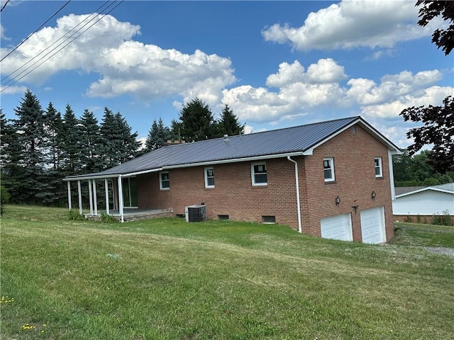 rear view of property featuring central AC, a garage, and a lawn