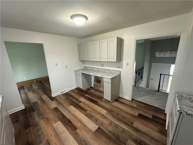 kitchen with white cabinetry, light stone countertops, and dark wood-type flooring