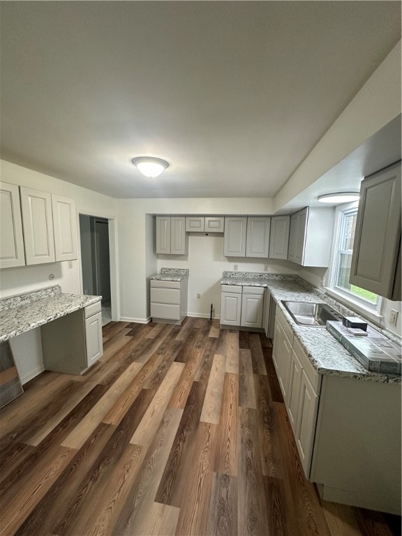 kitchen with sink, light stone countertops, dark hardwood / wood-style flooring, and gray cabinetry