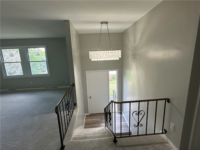 stairs featuring a chandelier, carpet floors, and a healthy amount of sunlight