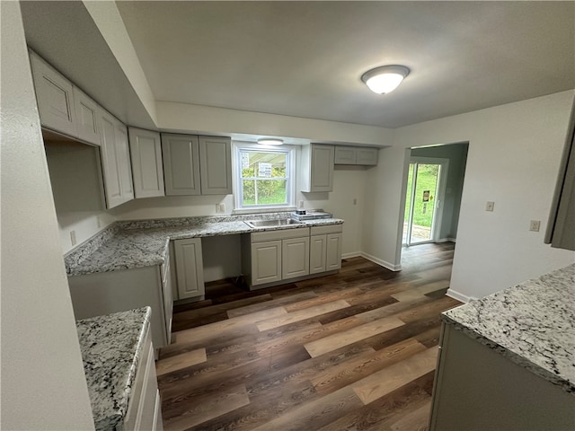 kitchen featuring gray cabinets, light stone countertops, dark wood-type flooring, and sink