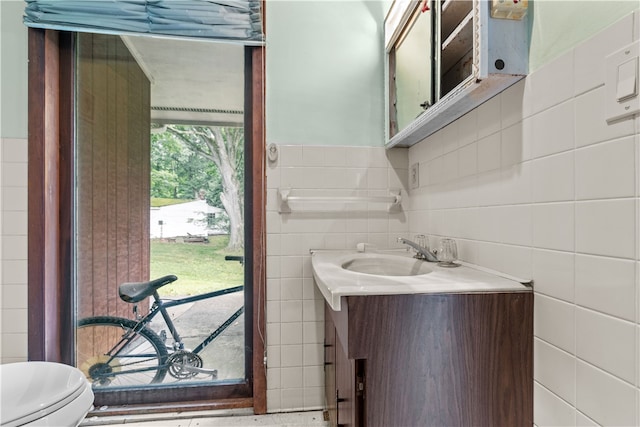 bathroom with vanity, decorative backsplash, tile walls, and toilet