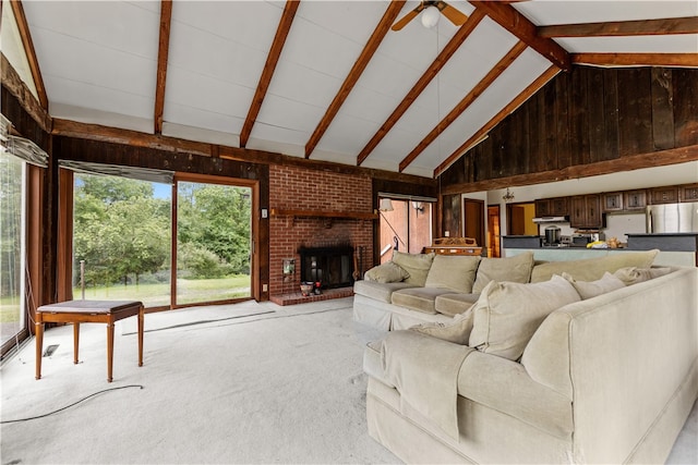 unfurnished living room featuring beamed ceiling, a fireplace, light colored carpet, high vaulted ceiling, and ceiling fan