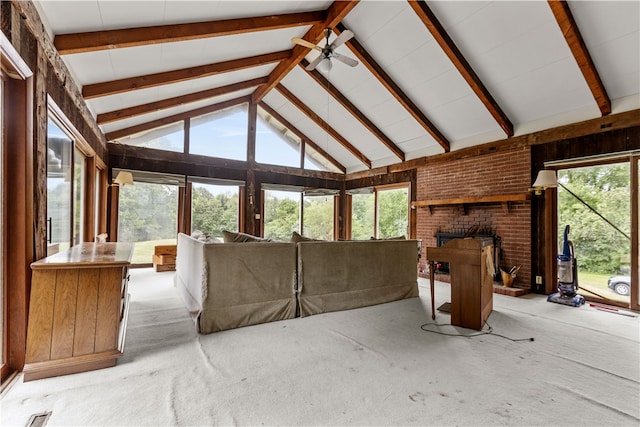 interior space featuring beamed ceiling, carpet flooring, a healthy amount of sunlight, and brick wall