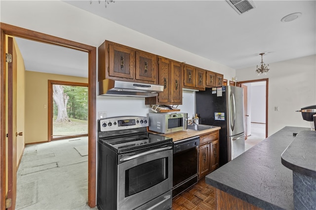 kitchen featuring a notable chandelier, appliances with stainless steel finishes, pendant lighting, and dark parquet flooring