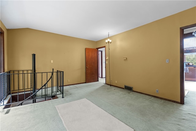 carpeted spare room with vaulted ceiling and a chandelier