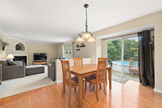 dining area featuring a wealth of natural light, ornamental molding, and light wood-type flooring