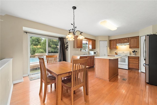 dining room with an inviting chandelier, sink, and light hardwood / wood-style floors