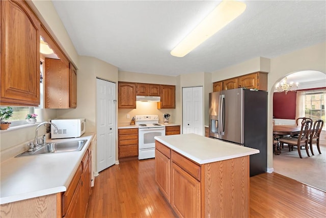 kitchen featuring sink, an inviting chandelier, wood-type flooring, a kitchen island, and white appliances