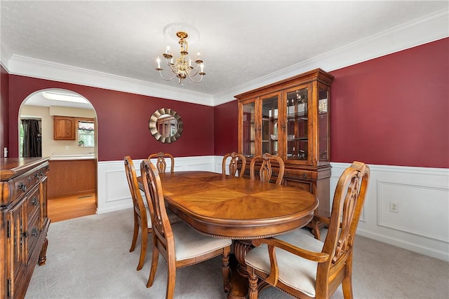 carpeted dining area featuring ornamental molding and a chandelier