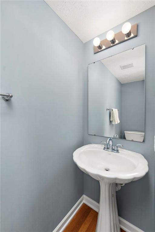 bathroom with hardwood / wood-style flooring and a textured ceiling