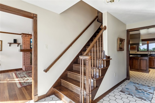 stairway with light tile patterned flooring, brick wall, and sink