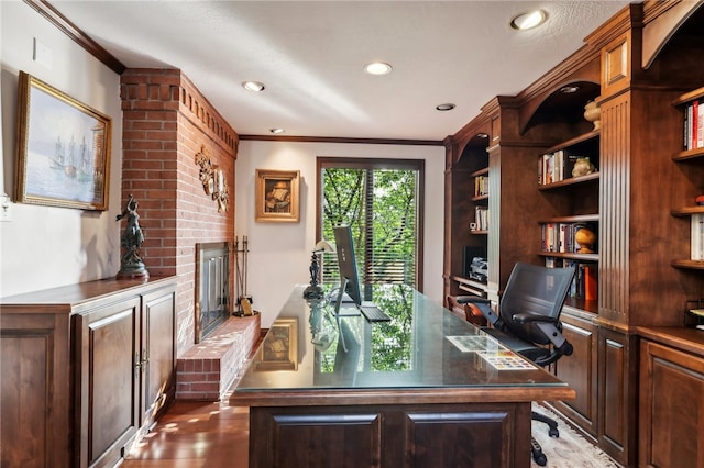 office with light hardwood / wood-style floors, ornamental molding, and a fireplace