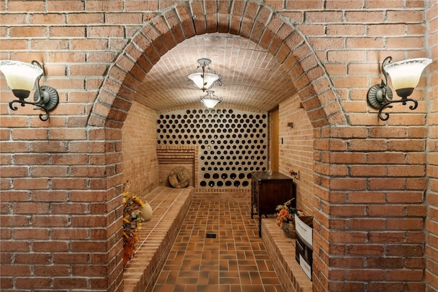 wine area featuring brick wall and lofted ceiling