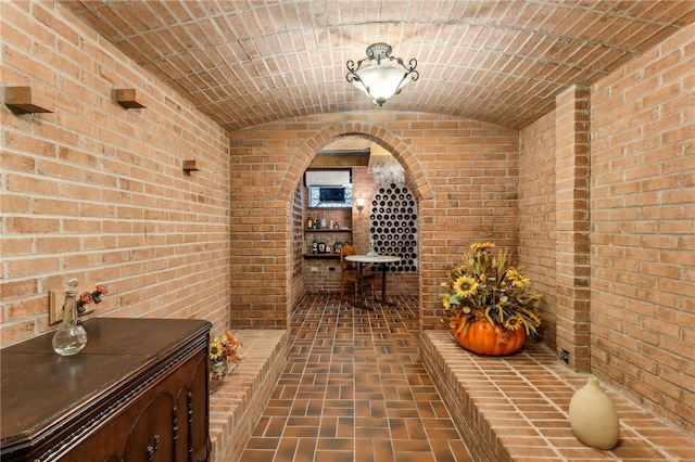 wine cellar with brick wall, brick ceiling, bar, and vaulted ceiling