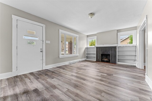 unfurnished living room featuring light hardwood / wood-style floors, a fireplace, and plenty of natural light