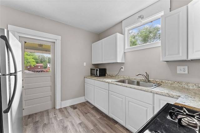 kitchen with white cabinetry, stainless steel appliances, light wood-type flooring, and plenty of natural light