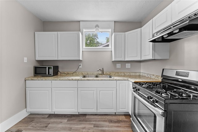 kitchen with white cabinetry, hardwood / wood-style flooring, stainless steel appliances, sink, and light stone counters