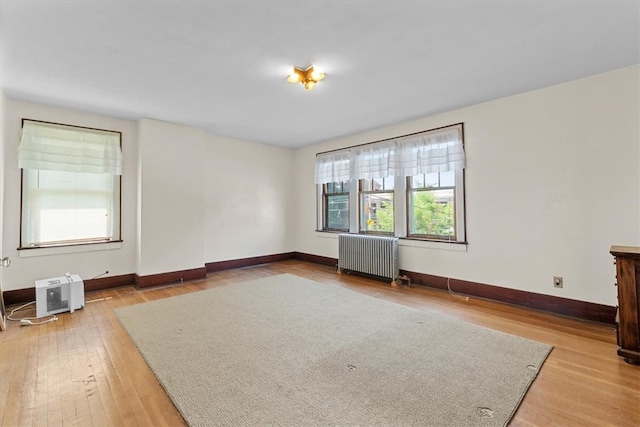 empty room with hardwood / wood-style floors and radiator heating unit