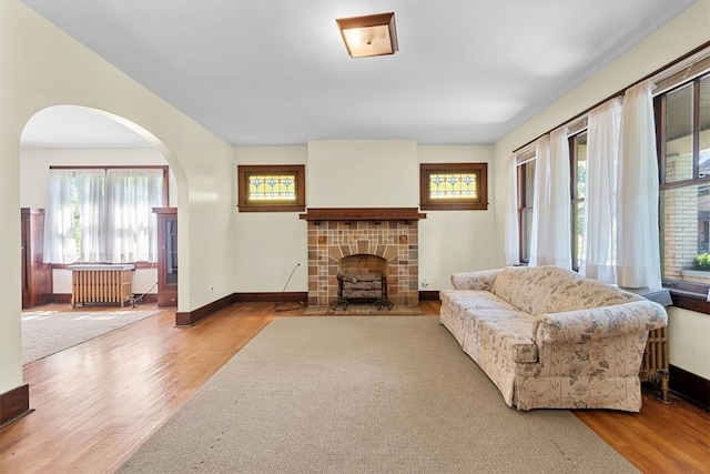 living room with radiator heating unit, a tiled fireplace, and hardwood / wood-style floors