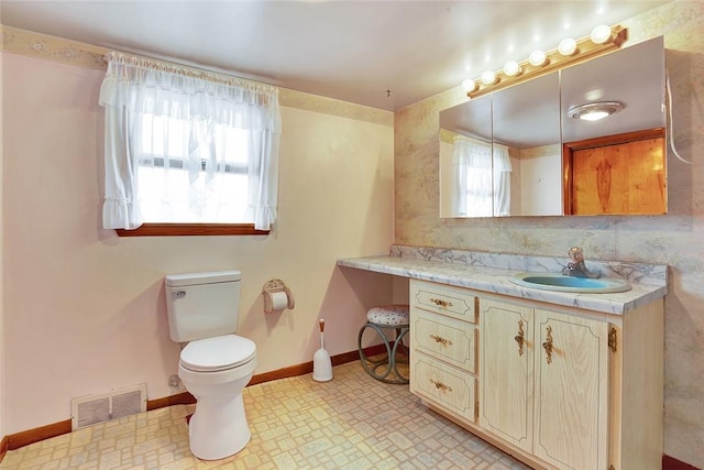 bathroom with vanity, tasteful backsplash, toilet, and a healthy amount of sunlight