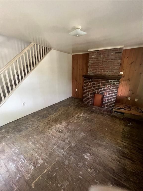 unfurnished living room featuring a brick fireplace and wooden walls