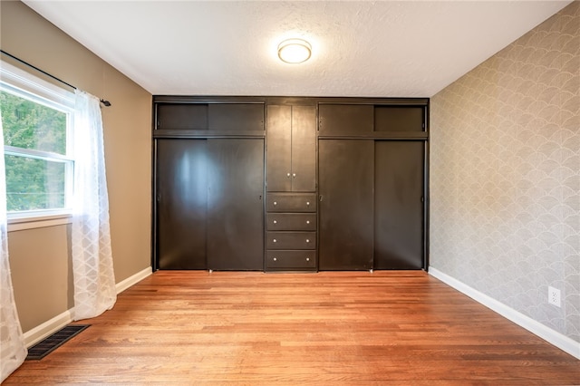 unfurnished bedroom with light wood-type flooring and a textured ceiling