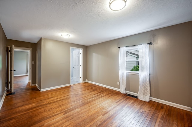 spare room featuring a textured ceiling and hardwood / wood-style flooring